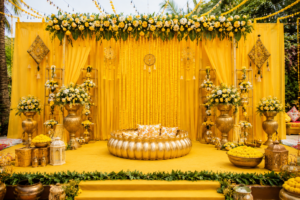 Luxury haldi ceremony decoration with yellow drapes, marigold flowers, floral backdrop and elegant stage setup for an Indian wedding.